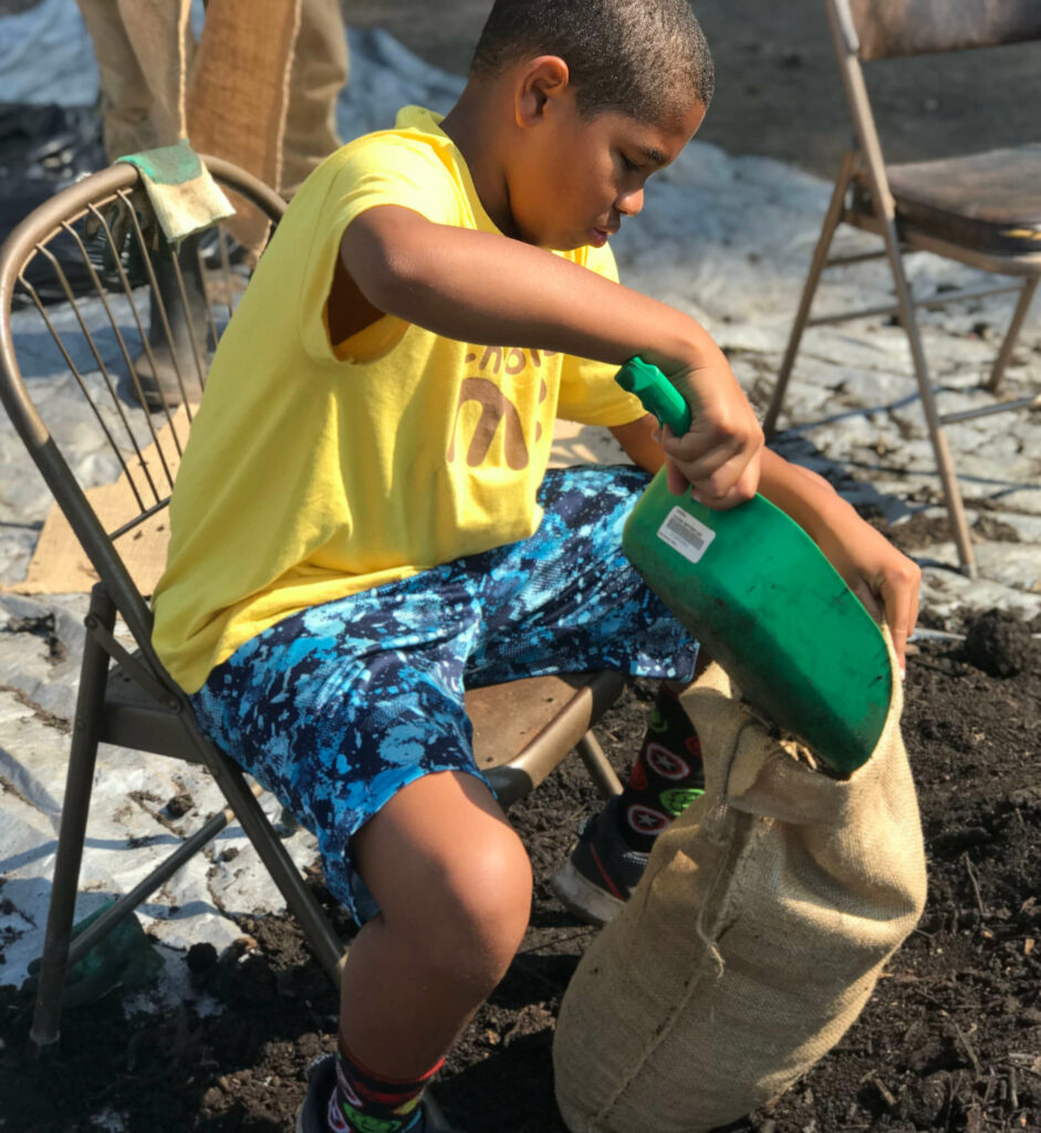 child putting compost in sack